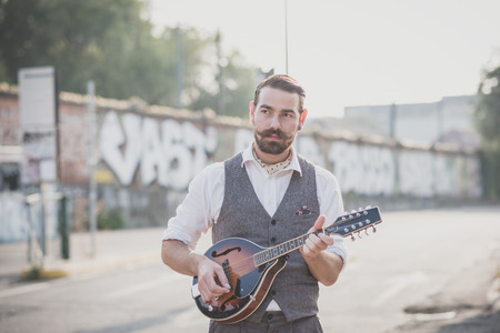 handsome big moustache hipster man playing mandolin in the cityの写真素材