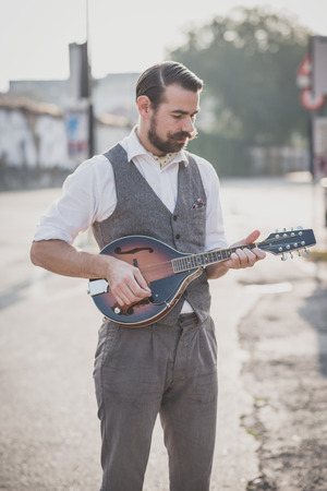handsome big moustache hipster man playing mandolin in the cityの写真素材
