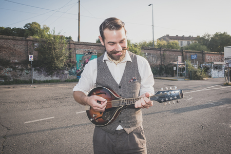 handsome big moustache hipster man playing mandolin in the cityの写真素材