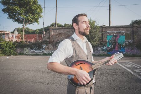 handsome big moustache hipster man playing mandolin in the cityの写真素材