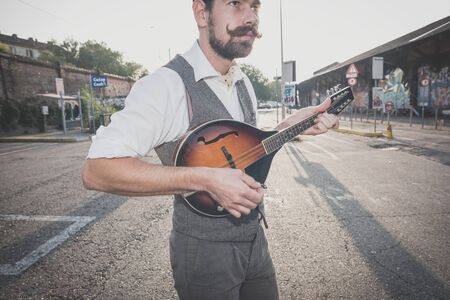 handsome big moustache hipster man playing mandolin in the cityの写真素材