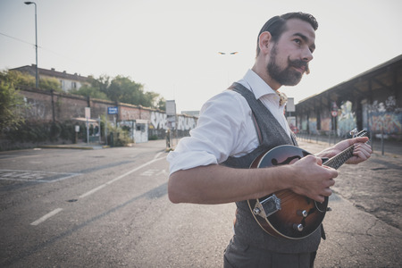 handsome big moustache hipster man playing mandolin in the cityの写真素材