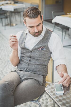 handsome big moustache hipster man using smart phone in the cityの写真素材