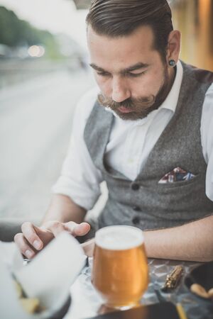 handsome big moustache hipster man using tablet sitting at the barの写真素材
