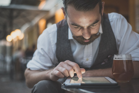 handsome big moustache hipster man using tablet sitting at the barの写真素材