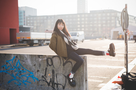 young beautiful asian hipster woman in the city - living town during sunset in backlitの写真素材