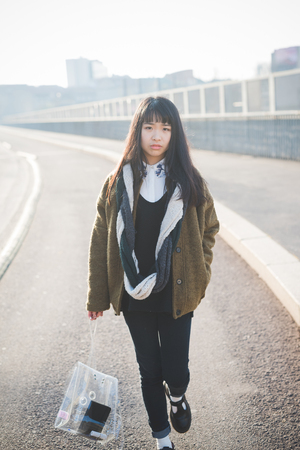 young beautiful asian hipster woman in the city - living town during sunset in backlitの写真素材