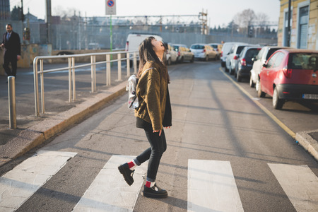 young beautiful asian hipster woman in the city - walking the street crosswalk having funの写真素材