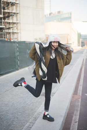 young beautiful asian hipster woman in the city - wearing funny piggy winter capの写真素材