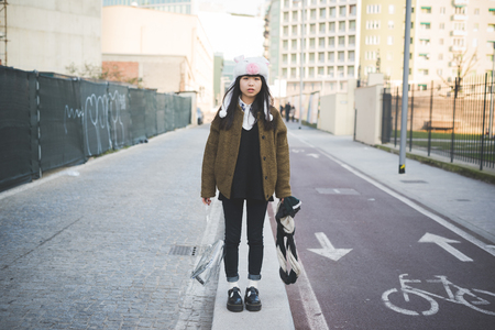 young beautiful asian hipster woman in the city - wearing funny piggy winter capの写真素材