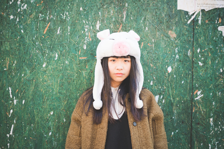 young beautiful asian hipster woman in the city - wearing funny piggy winter capの写真素材