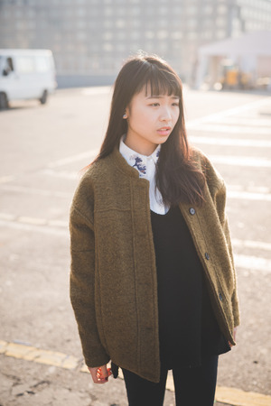 young beautiful asian hipster woman in the city - living town during sunset in backlitの写真素材
