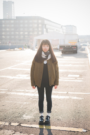 young beautiful asian hipster woman in the city - living town during sunset in backlitの写真素材