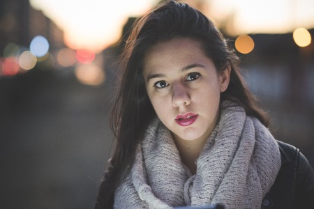 young beautiful long hair woman in town during sunset backlight using tabletの写真素材