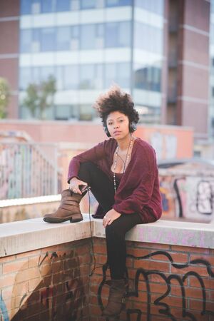 beautiful black curly hair african woman listening music with headphones in townの写真素材