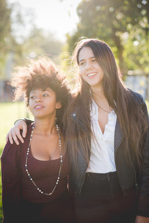 two multiethnic beautiful young woman black and caucasian having fun in townの写真素材