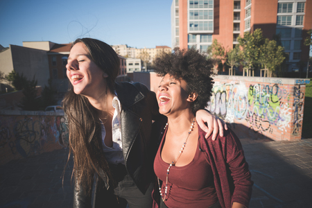 two multiethnic beautiful young woman black and caucasian having fun in townの写真素材