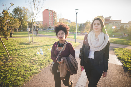 two multiethnic beautiful young woman black and caucasian having fun in townの写真素材