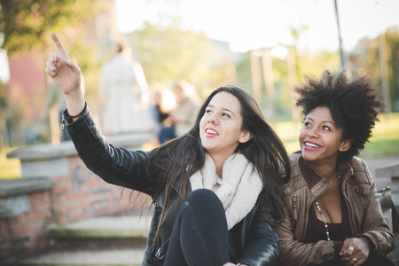two multiethnic beautiful young woman black and caucasian having fun in townの写真素材