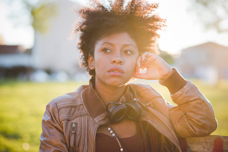 beautiful black curly hair african woman listening music with headphones in townの写真素材