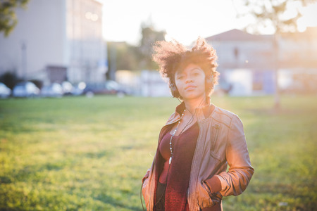beautiful black curly hair african woman listening music with headphones in townの写真素材