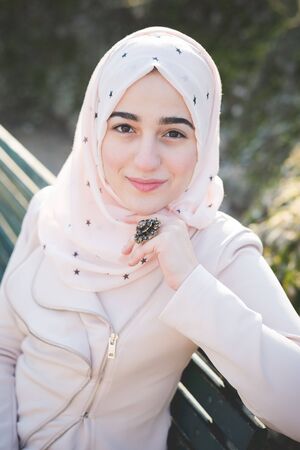 young beautiful muslim woman at the park in spring using smartphone connected online wirelessの写真素材