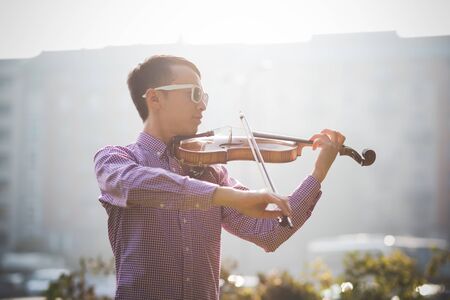 young crazy funny musician violinist asian man in town outdoor lifestyleの写真素材