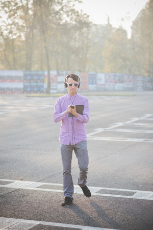 young crazy funny asian man in town outdoor lifestyle listening music with headphones and tabletの写真素材