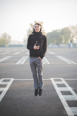 young crazy funny asian man in town outdoor lifestyle listening music with headphonesの写真素材
