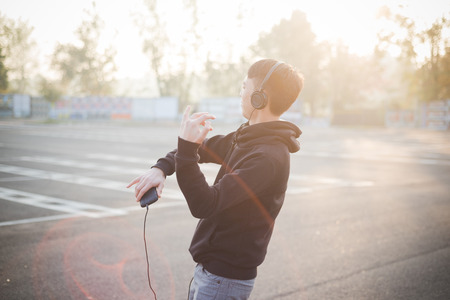 young crazy funny asian man in town outdoor lifestyle listening music with headphonesの写真素材