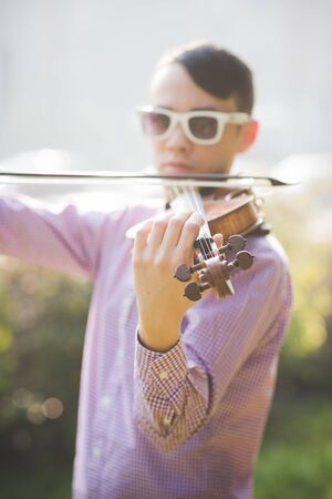 young crazy funny musician violinist asian man in town outdoor lifestyleの写真素材