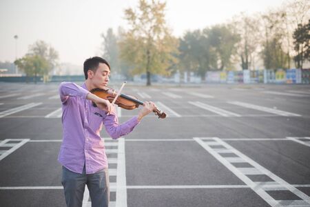 young crazy funny musician violinist asian man in town outdoor lifestyleの写真素材