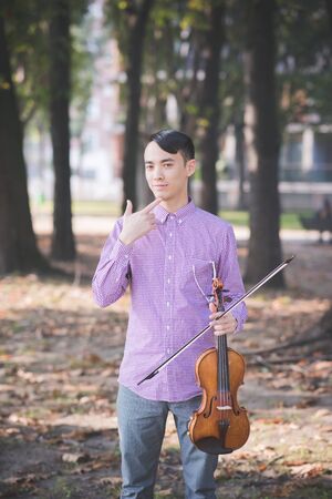 young crazy funny musician violinist asian man in town outdoor lifestyleの写真素材