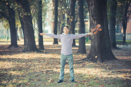 young crazy funny musician violinist asian man in town outdoor lifestyleの写真素材