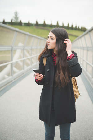 young beautiful long hair model woman living the city in winter outdoor city using smartphoneの写真素材