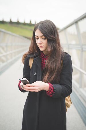 young beautiful long hair model woman living the city in winter outdoor city using smartphoneの写真素材