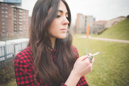 young beautiful long hair model woman living the city in winter outdoor city smoking cigaretteの写真素材