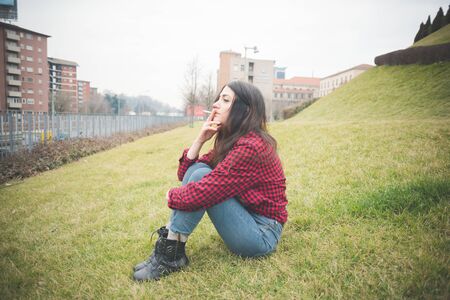 young beautiful long hair model woman living the city in winter outdoor city smoking cigaretteの写真素材