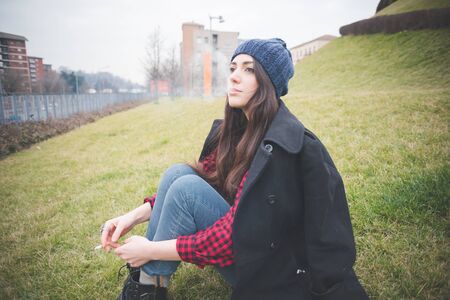 young beautiful long hair model woman living the city in winter outdoor city smoking cigaretteの写真素材