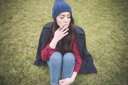 young beautiful long hair model woman living the city in winter outdoor city smoking cigaretteの写真素材