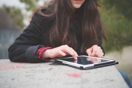 young beautiful long hair model woman living the city in winter outdoor city using tablet connected wireless onlineの写真素材