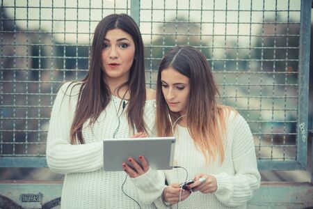 young couple beautiful women girls autumn using tablet outdoor