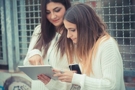 young couple beautiful women girls autumn using tablet outdoorの写真素材