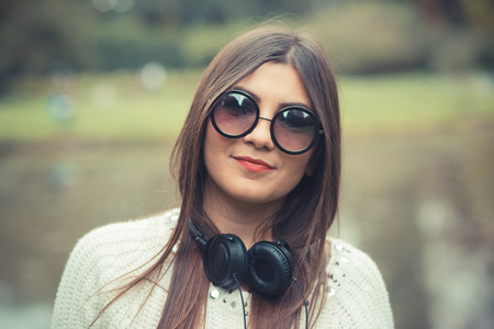 young beautiful brunette woman girl listening music headphones outdoorの写真素材