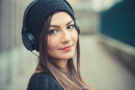 young beautiful brunette woman girl listening music headphones outdoorの写真素材
