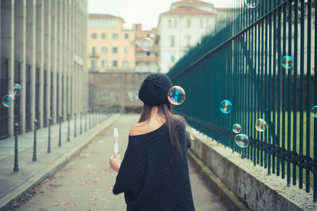 young beautiful brunette woman girl blowing bubbles soup outdoorの写真素材