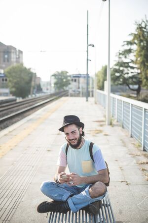 young handsome hipster gay modern man using smartphone in townの写真素材