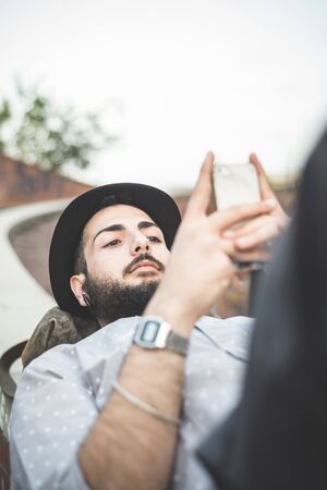 young handsome hipster gay modern man using smartphone in townの写真素材