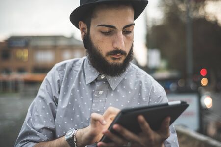 young handsome hipster gay modern man using tablet in town