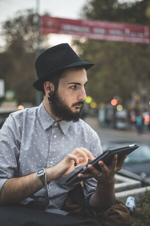 young handsome hipster gay modern man using tablet in townの写真素材